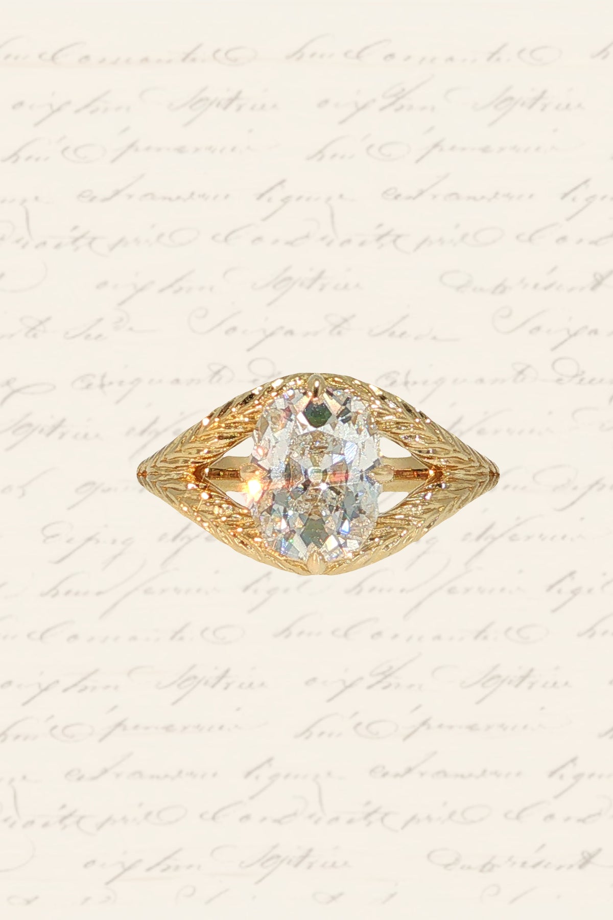 An engagement ring with a yellow gold old-world wheat hand-engraved band, a split shank, and four claw prongs in a compass setting around an old mine cut diamond.