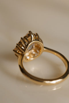 View from behind a yellow gold engagement ring showing the open gallery beneath the halo, with tall claw prongs rising around the stones and a smooth, rounded band.