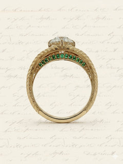 Side view of a Moonryvr engagement ring with a yellow gold, old-world, hand engraved, split shank band. The center stone is an old mine cut diamond with four claw prongs in a compass setting. The split shank has a hidden halo made of emeralds on the lower profile of the side view.